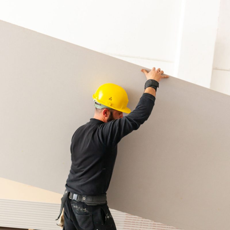 Worker builds a plasterboard wall. Worker at work in the construction of a plasterboard wall.